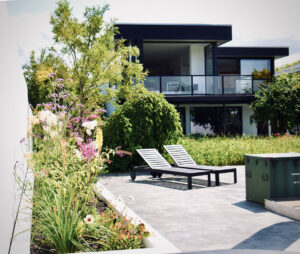 bloemen in de tuin met huis op achtergrond, solarlux kozijnen.
